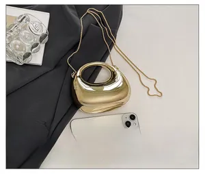 Size comparison of a gold acrylic mini chain bag next to a smartphone