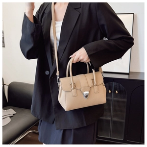Gros plan du sac Boston en cuir beige avec boucle en métal sur un mannequin en veste