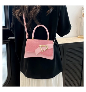 Detailed view of pink crossbody bag with woven texture flap and gold D-shaped buckle