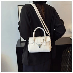Détail du sac Boston blanc texturé avec fermoir métallique porté par un mannequin