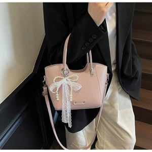 Sac seau en cuir rose avec grand nœud en dentelle et élégante breloque en perle