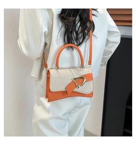 Detail of orange leather and beige fabric contrast handbag with a gold D-buckle closure