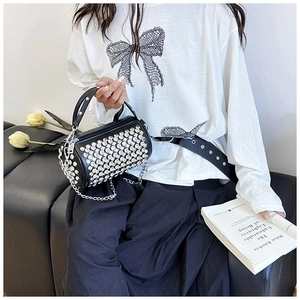 Detail of black cylinder bag with sparkling silver rhinestones and chain strap