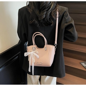 Détail du sac à main rose avec nœud en dentelle et perles porté par un mannequin
