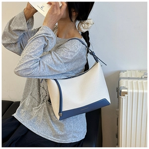 Model wearing a blue and white woven underarm bag with contrast leather trim details