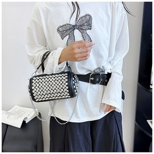 Detail of a black cylinder bag featuring sparkling rhinestones and a silver chain strap