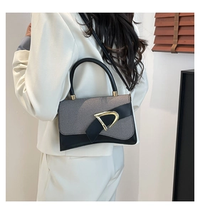 Detail of trendy crossbody bag featuring textured fabric and a gold D-buckle closure