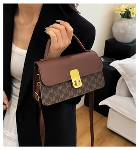 Close-up of retro brown monogram flap bag with textured leather and gold buckle finish