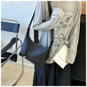 Detailed close-up of black textured underarm bag featuring silver hardware and wide strap