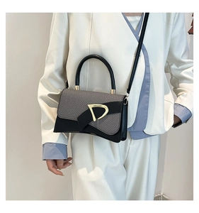 Detail of retro patchwork handbag with golden D-buckle shown on a white suit model