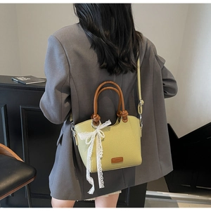 Sac seau vert citron en cuir grainé avec anses brunes et un nœud décoratif en dentelle