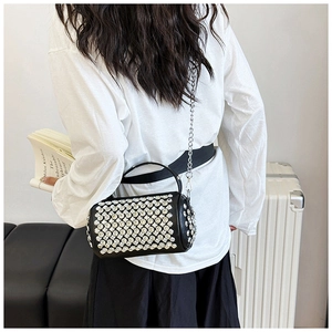 Detail view of a black cylinder bag with sparkling rhinestones and a metal chain strap