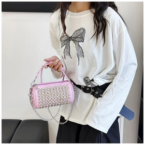 Detail of pink cylinder bag with shiny rhinestones and silver chain strap on model