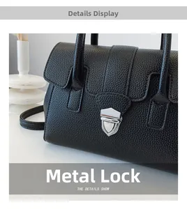 Gros plan du fermoir en métal argenté sur le sac Boston en cuir grainé noir