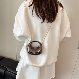Mini acrylic chain shoulder bag in glossy bronze finish shown on a white hoodie