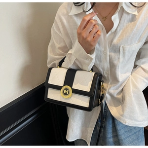 Detail of quilted diamond pattern on black and white handbag with golden M lock