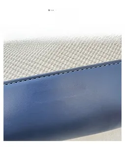 Close-up of beige woven fabric and navy leather stitching with gold logo detail