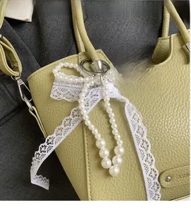 Détail du sac seau en cuir jaune avec un nœud décoratif en dentelle blanche et perles