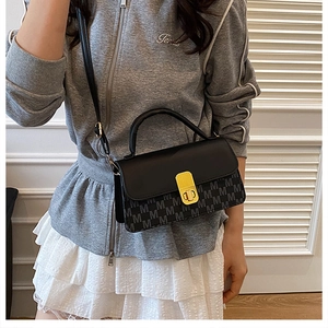 Detail view of women's crossbody bag with letter print and gold buckle on a model
