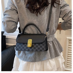Close-up of contrast crossbody bag with M-letter print and gold metal lock on model