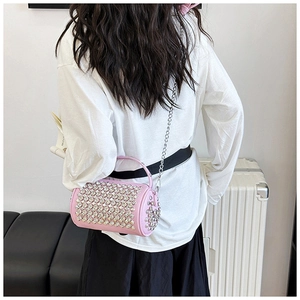 Lifestyle view of a pink rhinestone cylinder bag with a silver chain strap and top handle