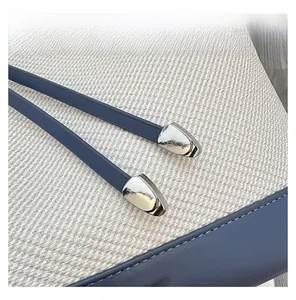 Macro shot of navy leather strap and silver hardware on a woven off-white tote bag