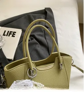 Détail du sac seau vert olive en cuir grainé avec anse métallique et breloques en perles