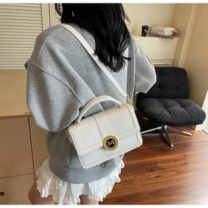 Rear view of a model wearing the white quilted PU leather crossbody bag with M-logo