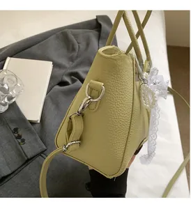 Détail du sac seau en cuir vert clair avec breloque en dentelle et perles décoratives