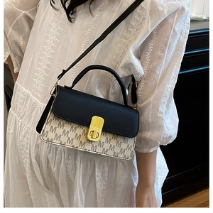 Détail d'un sac bandoulière bicolore avec imprimé lettres et fermoir doré chic