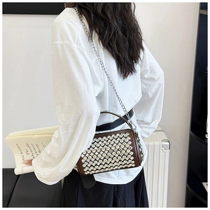 Detail of brown rhinestone cylinder bag with silver chain strap on fashion model
