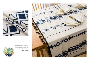 Detail of bohemian linen tablecloth featuring blue geometric prints and black tassels