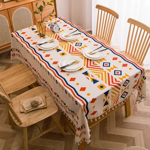 Bohemian linen tablecloth with colorful geometric patterns and white fringe on a wooden table