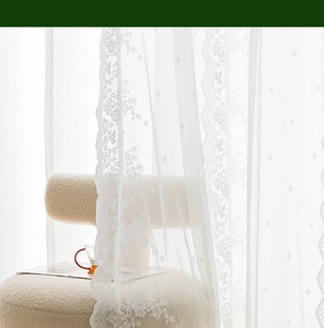 Detailed close-up of vintage white lace curtain featuring elegant floral embroidery textures