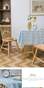 Close-up of Nordic light blue checkered tablecloth with white tassels on a wooden table
