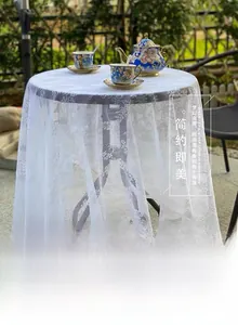 Detailed close-up of white floral lace tablecloth with intricate warp-knitted patterns