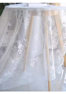 Detail of white lace tablecloth with floral embroidery and scalloped edges on wood