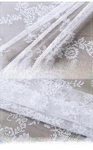 Macro detail of French white lace tablecloth featuring delicate floral embroidery patterns