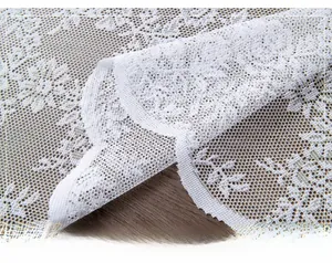 Close-up of white floral lace tablecloth with elegant scalloped edges on dark wood