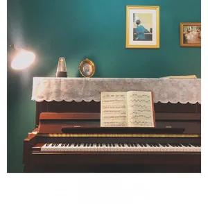 Close-up of white lace table runner on a vintage piano with classic accessories