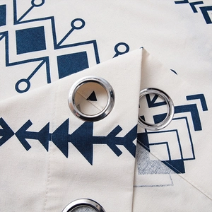 Detail of bohemian curtain with blue geometric patterns and silver metal grommets