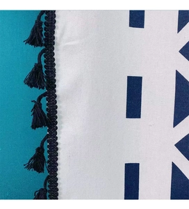 Detail of bohemian navy blue fringe tassel edge on white cotton linen fabric