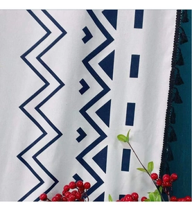 Detail of bohemian cotton linen fabric featuring navy geometric patterns and black tassels
