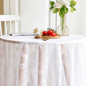 White French lace tablecloth with hollow floral patterns on a small round dining table