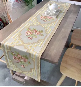 Close-up of pink floral embroidery and jacquard pattern on a beige table runner