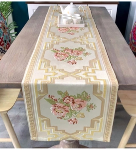 Detail of embroidered pink roses on beige chenille table runner with gold border