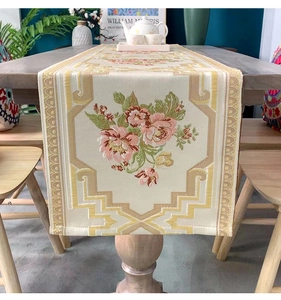 Close-up of elegant floral embroidery on beige chenille table runner with geometric borders