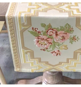 Detailed embroidery of pink peonies and golden patterns on a luxury chenille table runner