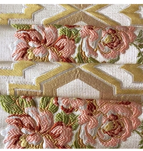 Macro detail of luxury chenille table runner featuring golden rhombic patterns and pink flowers