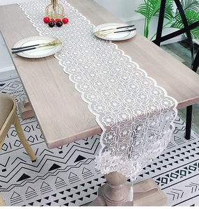 Close-up of white lace table runner with floral patterns and delicate fringe tassels